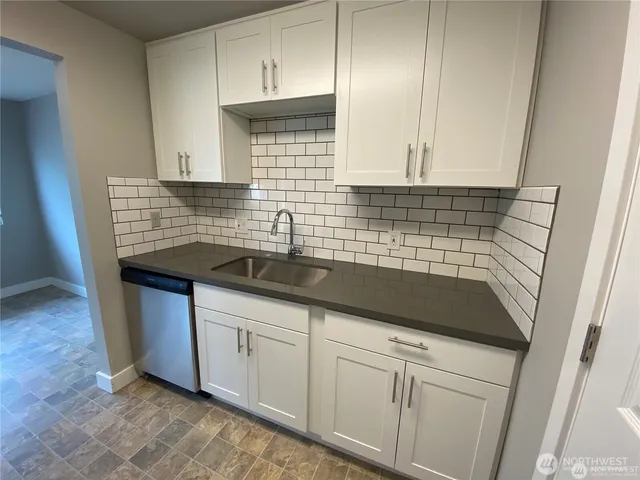 a kitchen with granite countertop a sink a stove and cabinets
