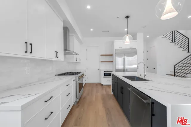 a large kitchen with stainless steel appliances kitchen island granite countertop a sink a stove and a wooden floors