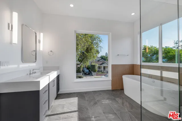 a spacious bathroom with a tub sink and mirror