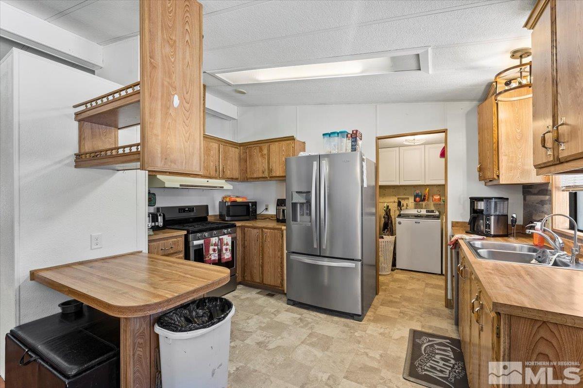 3867 Puffin Street Reno, NV 89508 - Photo 14 of 29 a kitchen with stainless steel appliances kitchen island granite countertop a refrigerator a stove and a sink