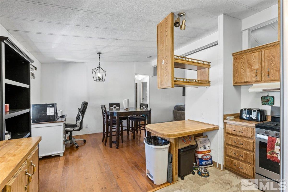 3867 Puffin Street Reno, NV 89508 - Photo 15 of 29 a kitchen with stainless steel appliances kitchen island granite countertop a table chairs in it and wooden floors