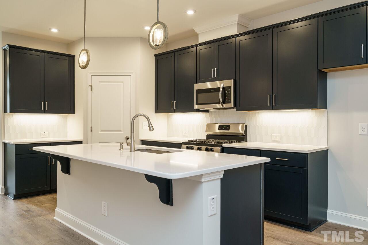 3113 Dunnock Drive, Unit 3 Durham, NC 27713 - Photo 11 of 30 a kitchen with kitchen island a sink stainless steel appliances and cabinets