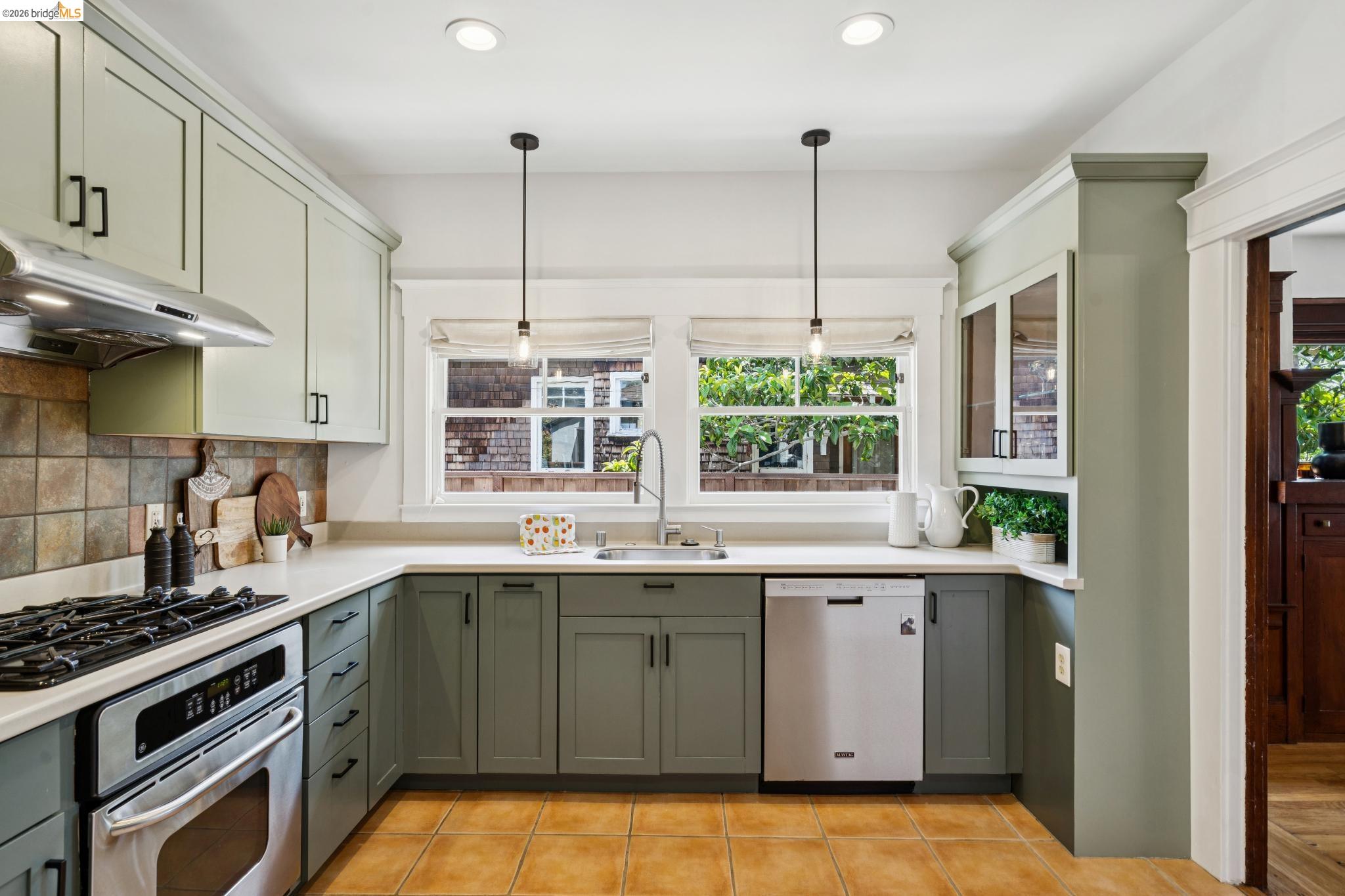 1701 Derby Street Berkeley, CA 94703 - Photo 20 of 39 U-shaped kitchen featuring two-tone cabinetry, stainless steel appliances including a gas range and dishwasher, and a tile backsplash