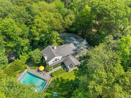 an aerial view of residential house with outdoor space and trees all around