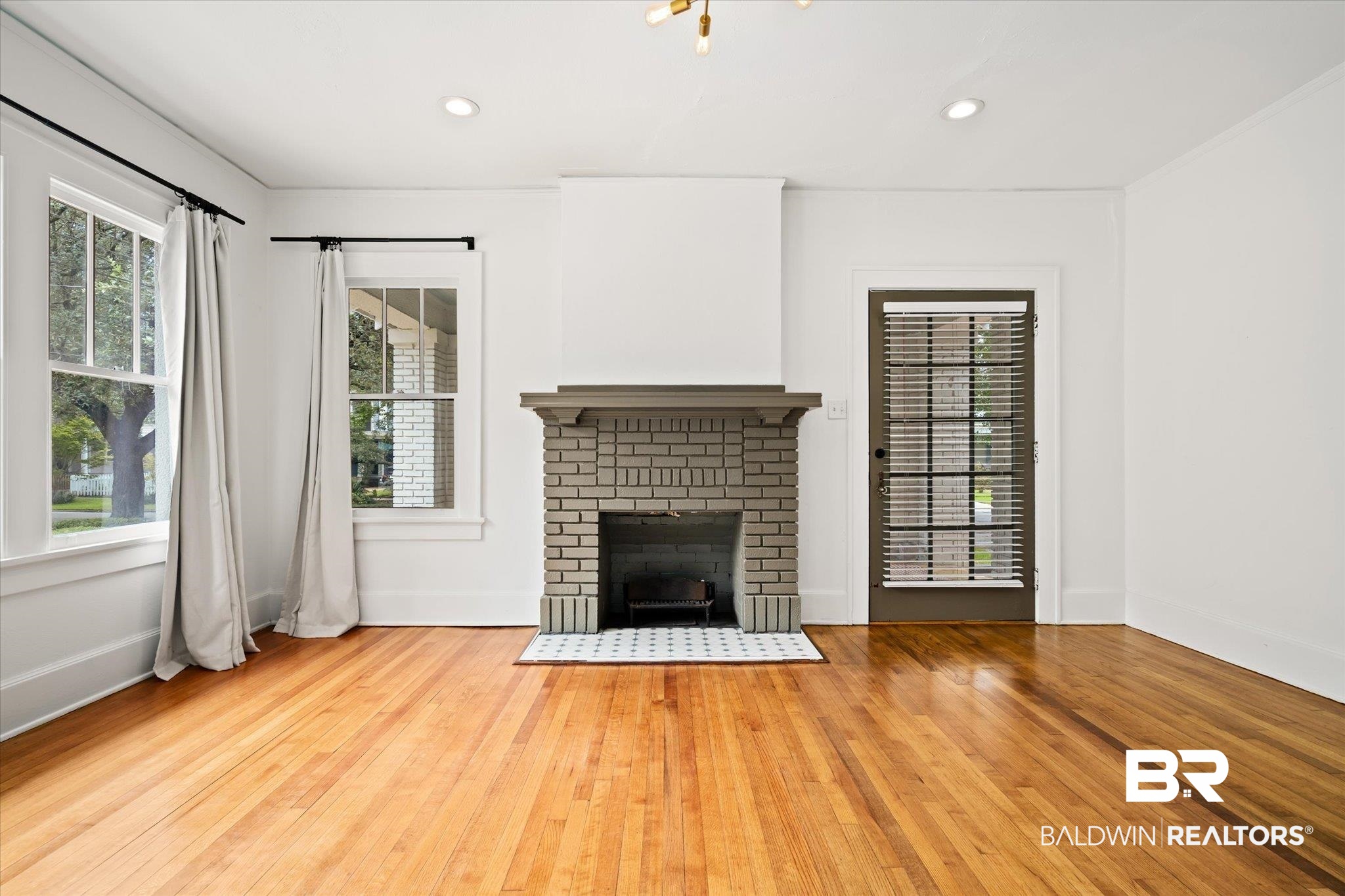 308 South Ann Street Mobile, AL 36604 - Photo 4 of 30 Unfurnished living room featuring plenty of natural light, light hardwood / wood-style flooring, and a brick fireplace