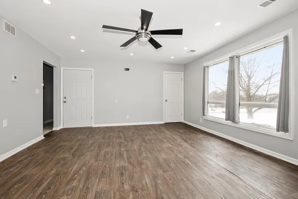 a view of an empty room with a window and wooden floor