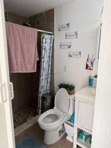 a white toilet sitting next to a bathroom sink and a shower