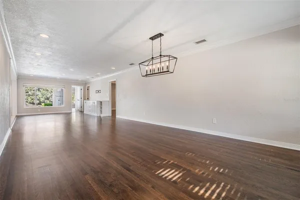 a view of an empty room with wooden floor and windows