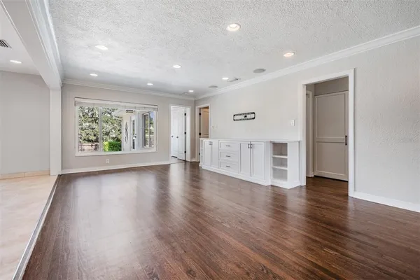 a view of an empty room with wooden floor and windows