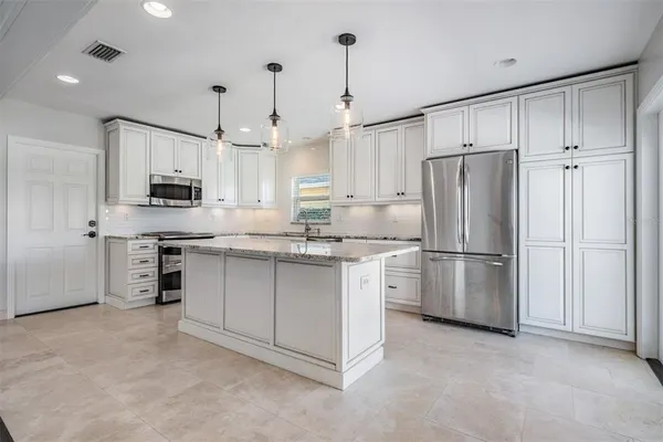 a kitchen with kitchen island white cabinets and stainless steel appliances