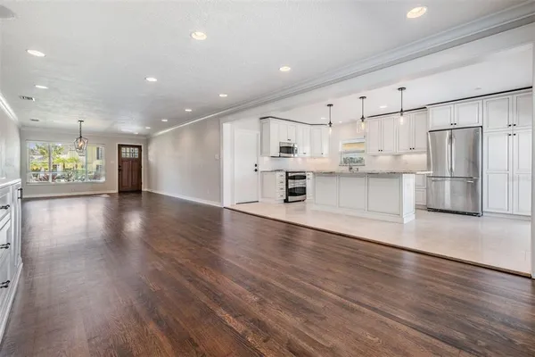 a view of kitchen with stainless steel appliances refrigerator oven stove microwave and wooden floor
