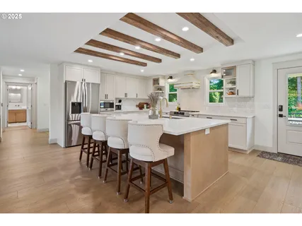 a kitchen with stainless steel appliances kitchen island granite countertop a table chairs and wooden cabinets
