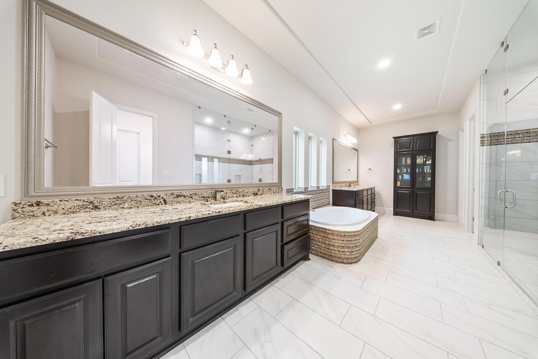 5403 Rouchel Brook Lane Sugar Land, TX 77479 - Photo 15 of 42 Spa-like primary bathroom featuring dual vanities, framed mirrors, soaking tub, built-in linen storage and oversized walk-in shower.