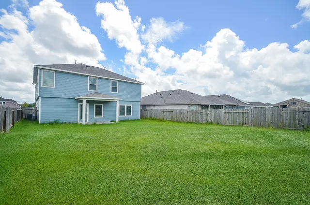 a view of a house with a yard and a large tree