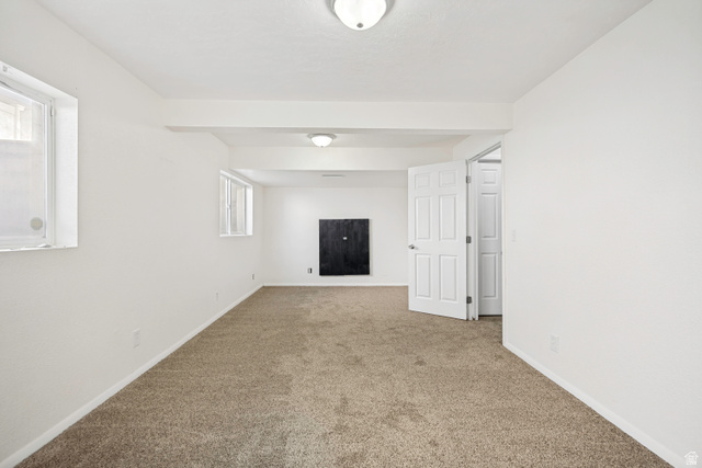 5529 Ridge Hollow Way Kearns, UT 84118 - Photo 17 of 23 Spacious room featuring neutral carpeting, white walls, and multiple ceiling-mounted light fixtures