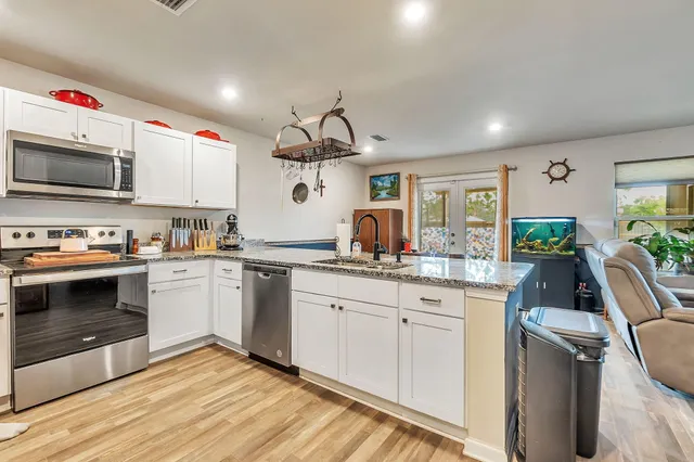 a kitchen with granite countertop a sink stainless steel appliances and cabinets