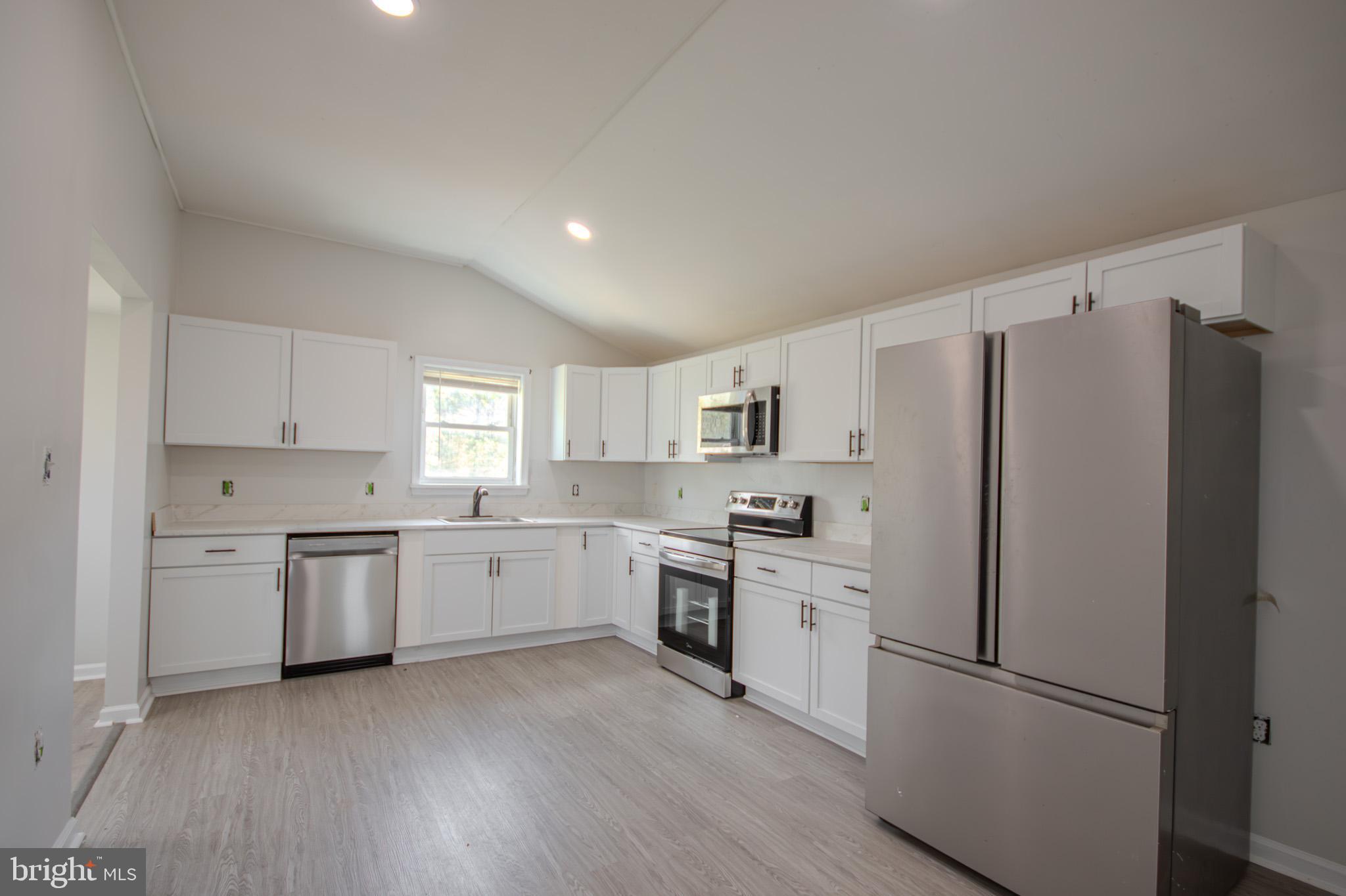 5693 Landon Store Road Marion Station, MD 21838 - Photo 3 of 20 a kitchen with white cabinets and stainless steel appliances