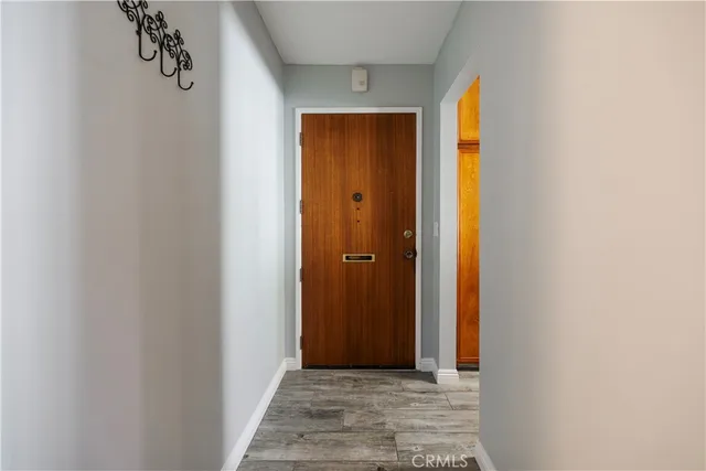 a view of a hallway with wooden floor and a bathroom
