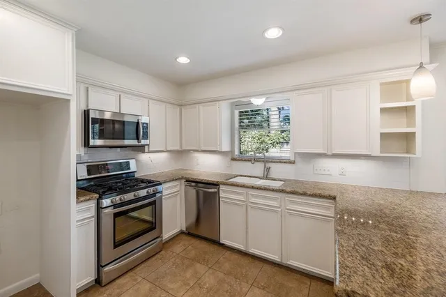 a kitchen with stainless steel appliances granite countertop a sink dishwasher stove and oven