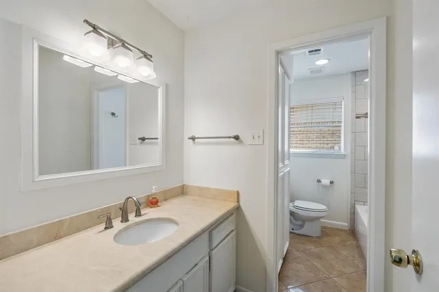 a bathroom with a sink vanity granite toilet and a mirror