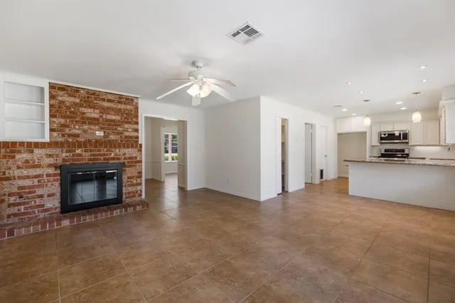 a view of a livingroom with a fireplace a ceiling fan and windows