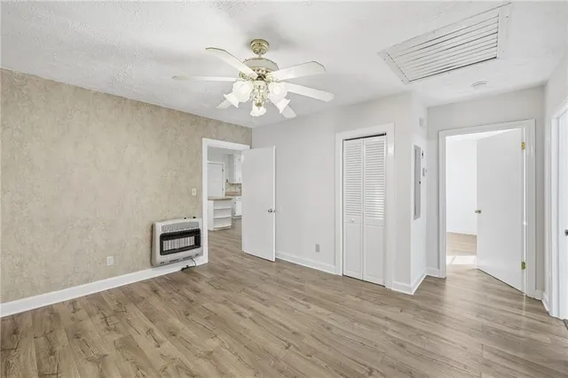 an empty room with wooden floor chandelier fan and windows