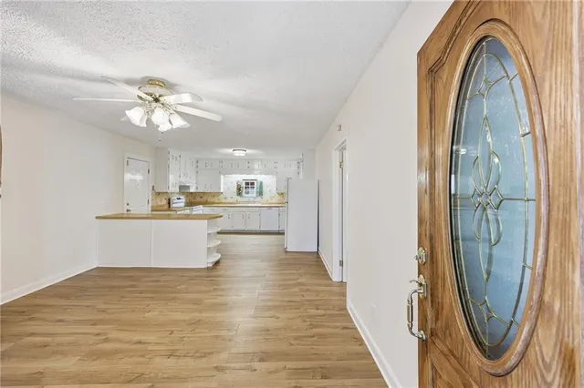 a view of a kitchen with kitchen island a refrigerator a sink dishwasher a dining table and chairs with wooden floor