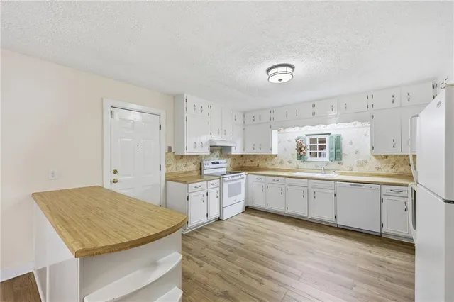 a kitchen with cabinets appliances wooden floor and a window