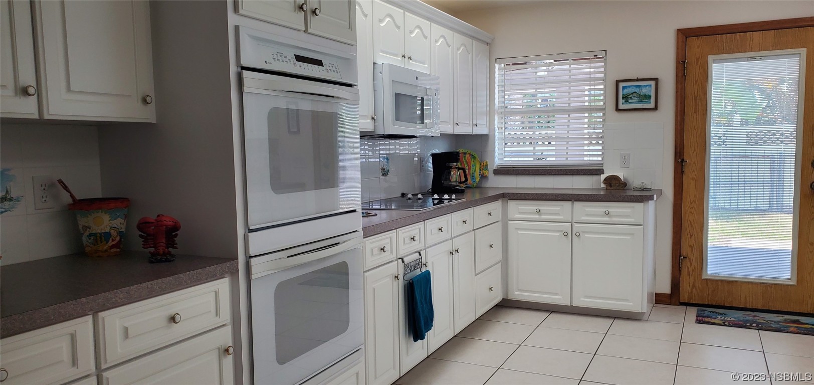 239 Kirkland Road New Smyrna Beach, FL 32169 - Photo 19 of 36 a kitchen with granite countertop white cabinets and white appliances