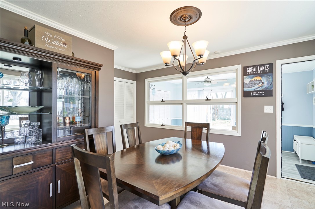28322 Forest Road Willowick, OH 44095 - Photo 12 of 32 Dining space with ceiling fan with notable chandelier, crown molding, and light vinyl floors