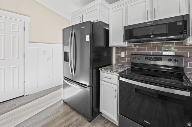 5525 Hampton Way Stansbury Park, UT 84074 - Photo 8 of 35 Kitchen area featuring white cabinetry, granite-style countertops, stainless steel refrigerator, black electric range with an overhead microwave, and a brown subway tile backsplash
