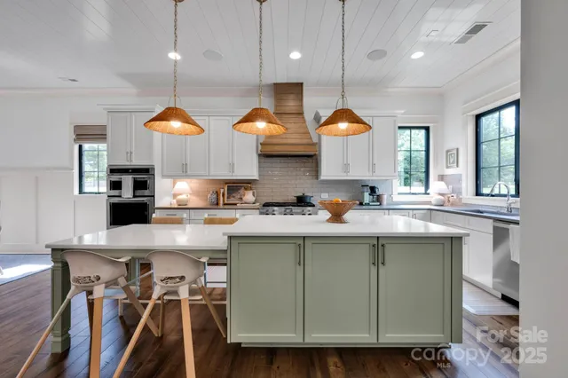 a kitchen with stainless steel appliances granite countertop a stove a refrigerator a oven a dining table and chairs with wooden floor