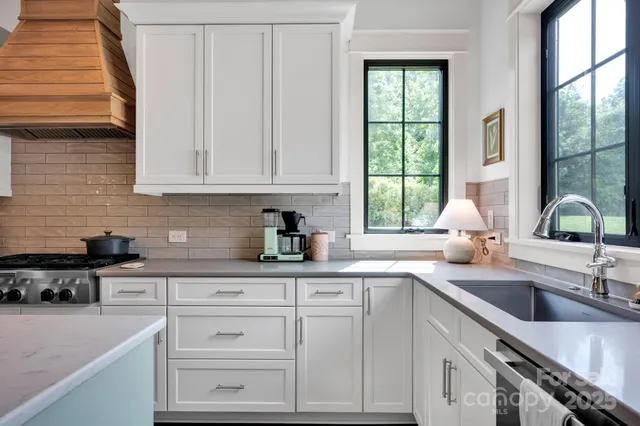 a kitchen with granite countertop a sink window and cabinets