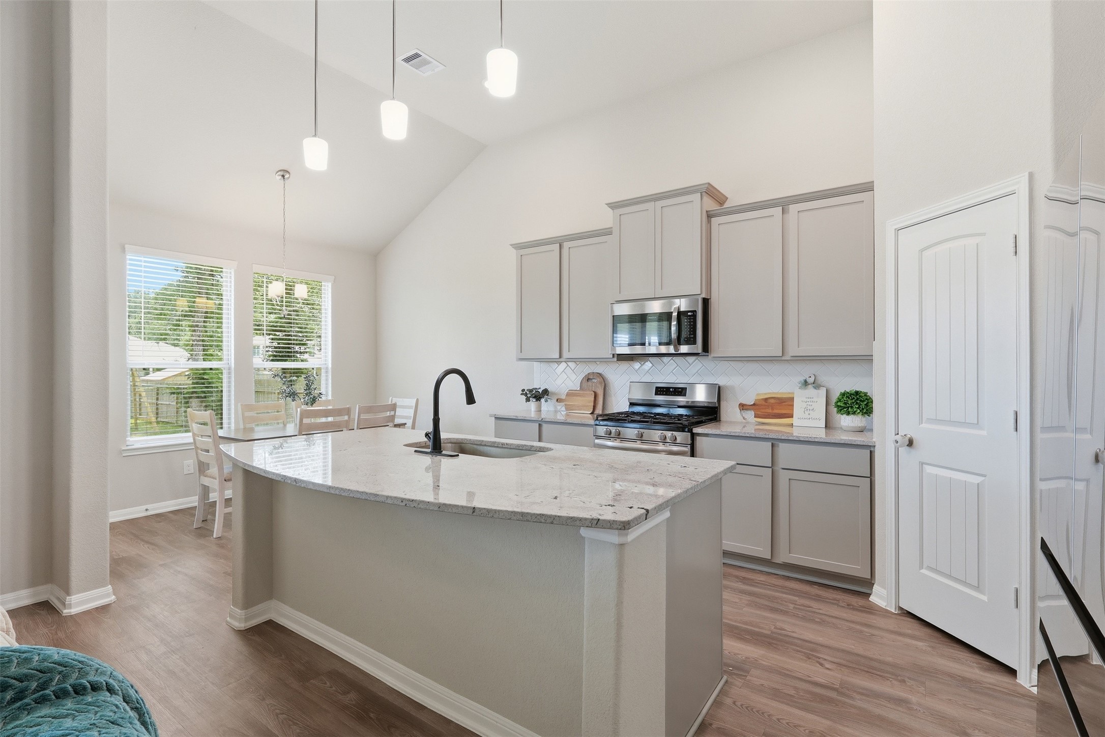 6310 Fawn Path Drive Conroe, TX 77303 - Photo 15 of 41 Chef-inspired kitchen featuring a large island, stainless steel appliances, upgraded cabinetry, high ceilings, and a bright dining area filled with natural light.