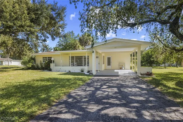 a view of a house with a yard and large tree