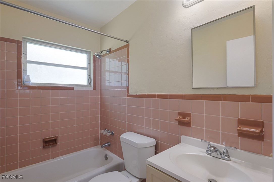 112 Clayton Avenue Lehigh Acres, FL 33936 - Photo 14 of 21 a bathroom with a toilet a sink a mirror and bathtub