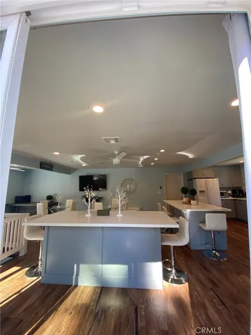 a open kitchen with kitchen island a sink white cabinets and chairs