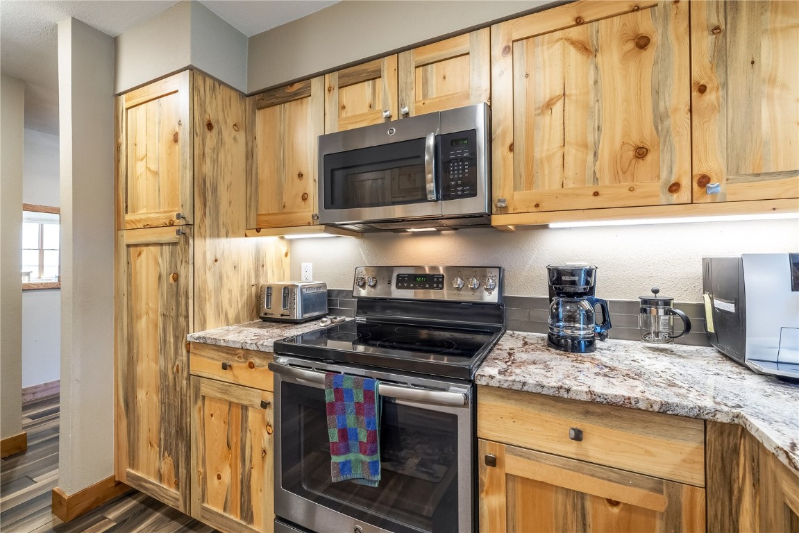 180 Tennis Club Road, Unit 1636 Keystone, CO 80435 - Photo 12 of 34 Kitchen with appliances with stainless steel finishes, dark hardwood / wood-style flooring, and light stone countertops