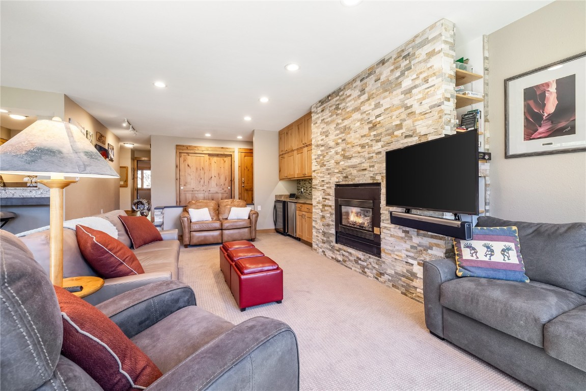 180 Tennis Club Road, Unit 1636 Keystone, CO 80435 - Photo 3 of 34 Living room featuring built in shelves, a stone fireplace, and light carpet