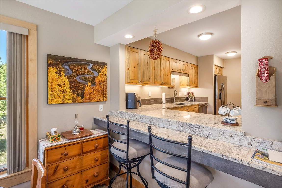 180 Tennis Club Road, Unit 1636 Keystone, CO 80435 - Photo 9 of 34 Kitchen with a kitchen breakfast bar, light stone counters, stainless steel fridge with ice dispenser, and sink