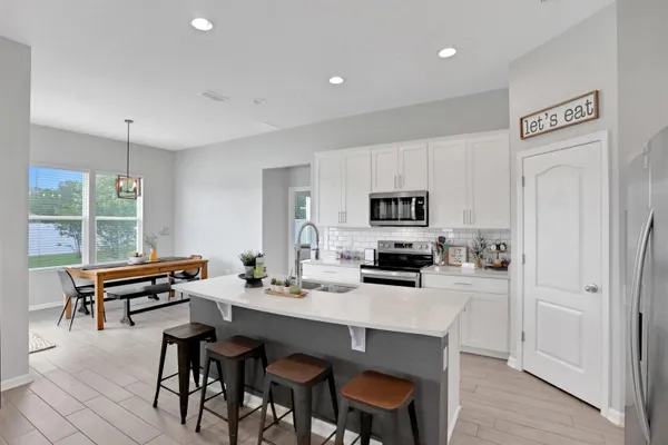 a kitchen with a dining table chairs and refrigerator