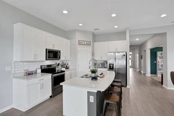 a kitchen with stainless steel appliances a stove a sink a dining table and chairs