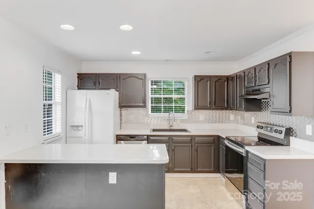 a kitchen with stainless steel appliances a sink a stove a refrigerator and cabinets