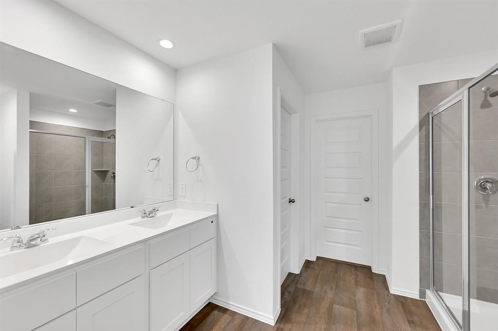 31006 Brightwell Bend Fulshear, TX 77441 - Photo 14 of 47 a bathroom with a double vanity sink a mirror and a shower