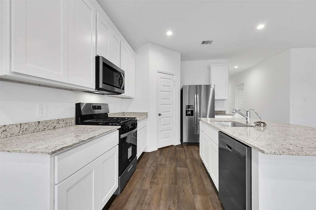 31006 Brightwell Bend Fulshear, TX 77441 - Photo 3 of 47 a kitchen with stainless steel appliances granite countertop a sink stove microwave and refrigerator