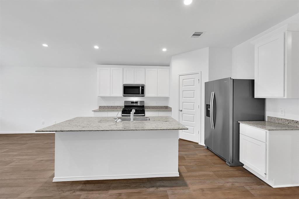 31006 Brightwell Bend Fulshear, TX 77441 - Photo 5 of 47 a kitchen with stainless steel appliances granite countertop a refrigerator a stove a sink and a microwave