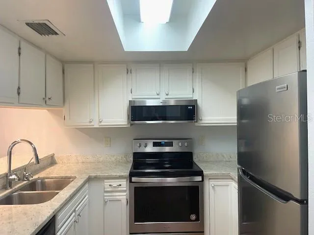 a kitchen with stainless steel appliances granite countertop a stove a refrigerator and a sink with cabinets