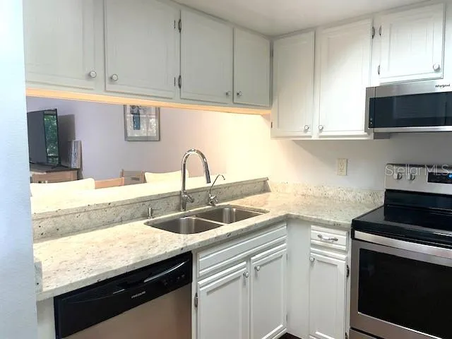 a kitchen with granite countertop a sink dishwasher stove and cabinets with wooden floor