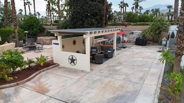 a view of a patio with table and chairs potted plants and large tree