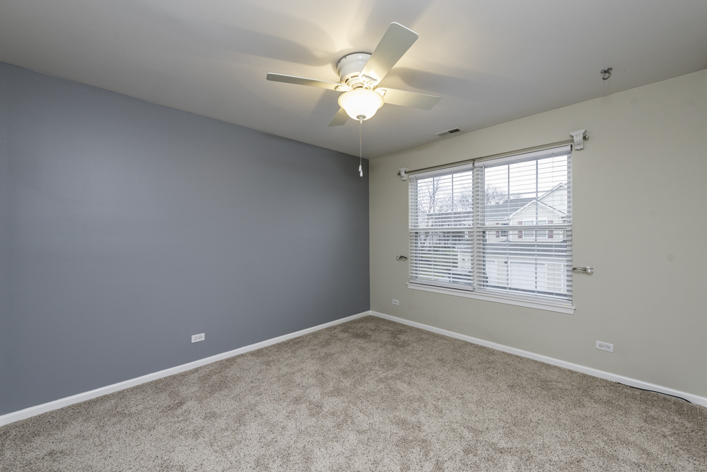 2879 Falling Waters Drive, Unit 2879 Lindenhurst, IL 60046 - Photo 19 of 30 an empty room with chandelier fan and windows